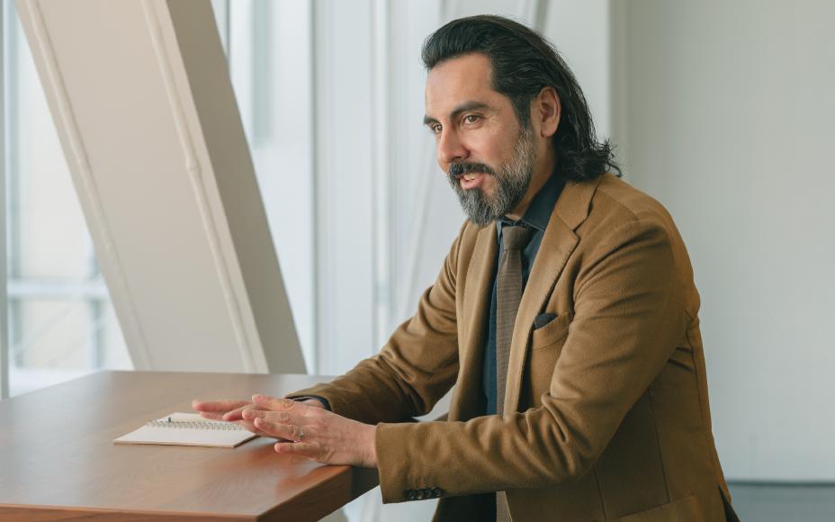 A person in a brown jacket placing his hands on a table