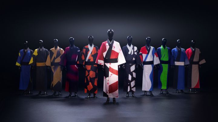 Black mannequins stand in a row wearing different, colorful kimonos against a black background.