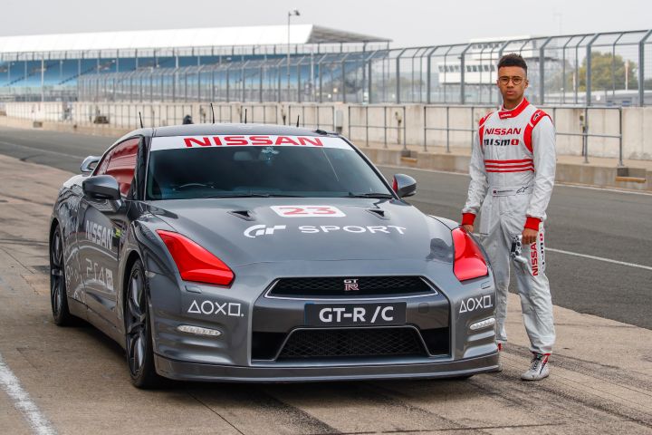 A person posing for a photo near the grey remote controlled GT‑R