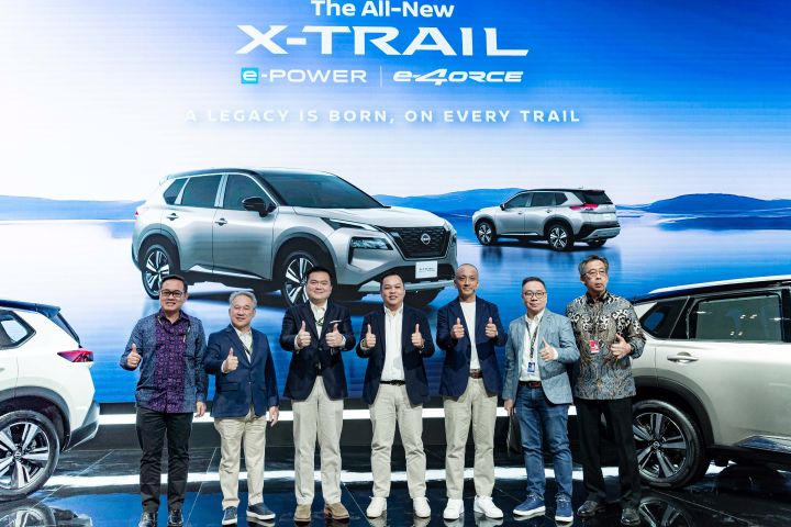 A group of representatives from NMDI , Nissan and distinguished guests standing on the stage with their thumb up.