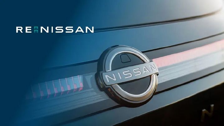 Imagem com foco no brand symbol da parte frontal de um veículo Nissan e na parte superior esquerda a palavra RE:NISSAN