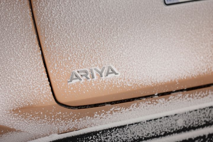 Verschneite Heckpartie des Elektroautos Nissan Ariya e‑4ORCE in Akatsuki Copper mit Ariya Schriftzug