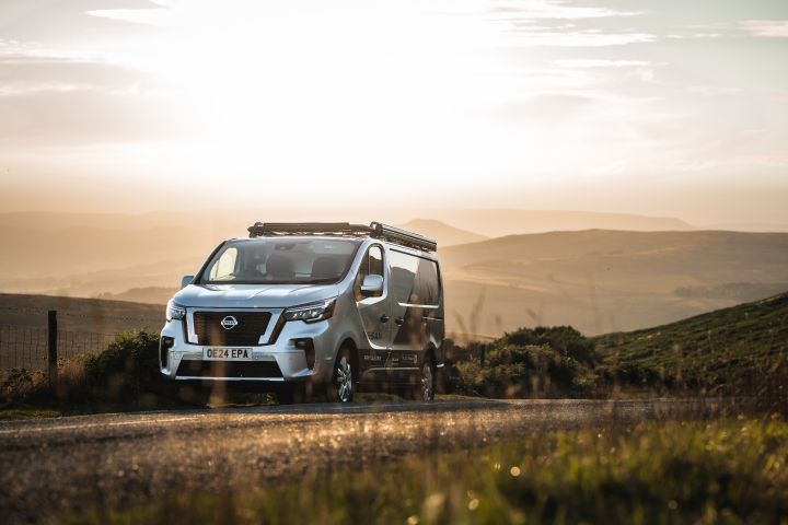 The Ride Companion’s converted Nissan Primastar parked by the side of a road at sunset with a landscape of beautiful rolling hills behind it