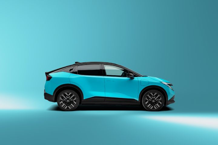 Welcoming the all-new Nissan LEAF - Profile view of new LEAF in luminous teal color showing charging port, Ni-San pattern wheels, side doors, clear front windows, glazed rear windows, bumpers and flush door handles