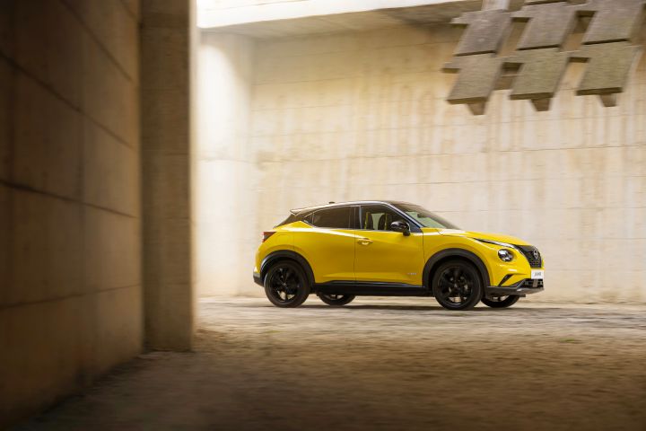 Seitliche Fahraufnahme gelber Nissan Juke auf hellem Untergrund vor hellem Hintergrund