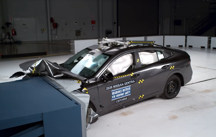 A test vehicle that has struck and object, the hood is caved in, testing stickers are visible.