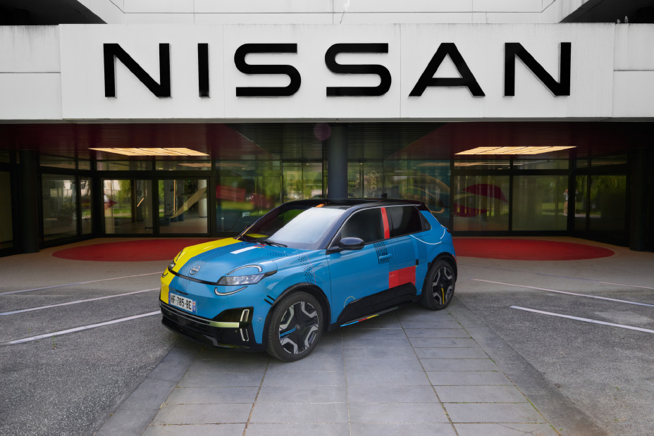 Nissan MICRA with blue body, yellow front panel and red design accents parked outside Nissan Europe HQ, with a large “NISSAN” sign above the entrance.