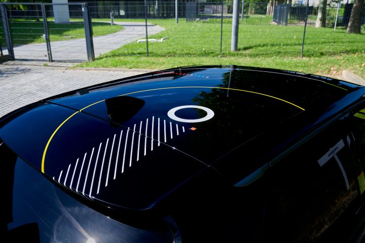 Nahaufnahme eines schwarzen MICRA-Dachs mit glänzender Oberfläche, einer weißen kreisförmigen Grafik, diagonalen Linienmustern und feinen gelben Akzenten, aufgenommen im Freien.