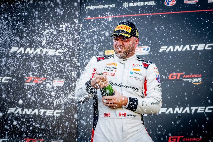 Nissan driver Damir Hot on the podium in a white race suit shooting celebratory champaign