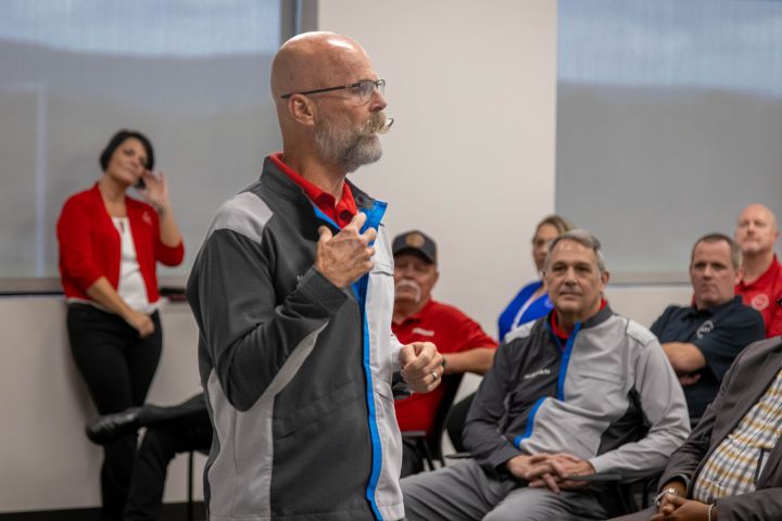 David Sliger in a gray and blue Nissan Jacket speaking with intention to a crowd of workers
