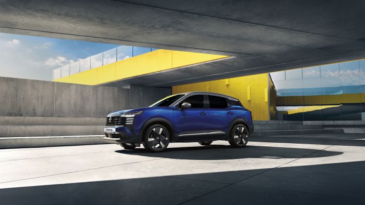 Side shot of the all-new Nissan KICKS in blue, parked under a yellow bridge.