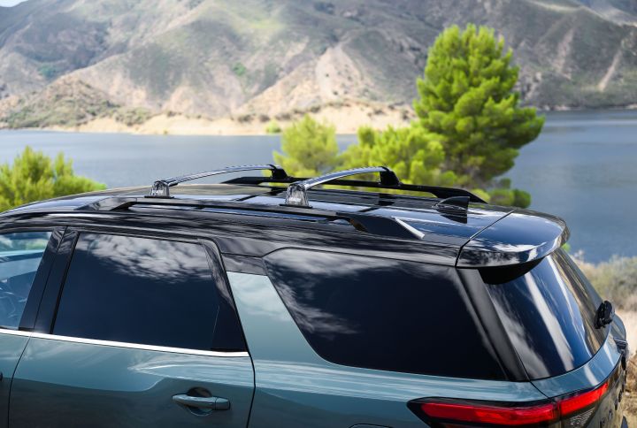 Top side view of the 2026 Nissan Pathfinder parked near trees, mountains and water.