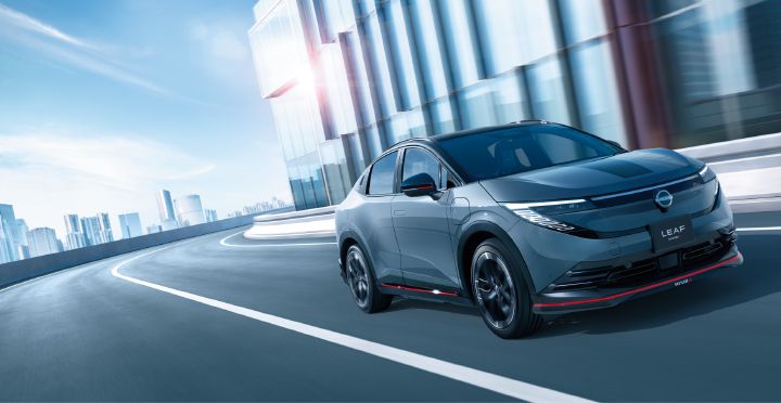 Image dynamique de ¾ avant d’une LEAF NISMO sur une route entre des immeubles