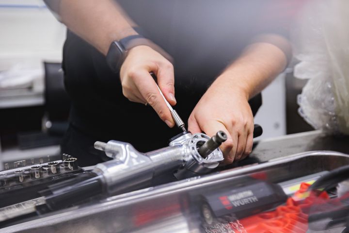 Nahaufnahme von Händen, die an einem Bauteil des Nissan Formel E Rennbolidens schrauben