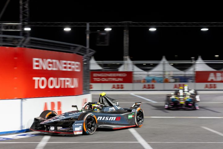 Oliver Rowland fährt im Nissan e‑4ORCE 05 mit der Startnummer 1 nach rechts in eine Kurve ein; rechts im Bild sind zwei Autos zu sehen.