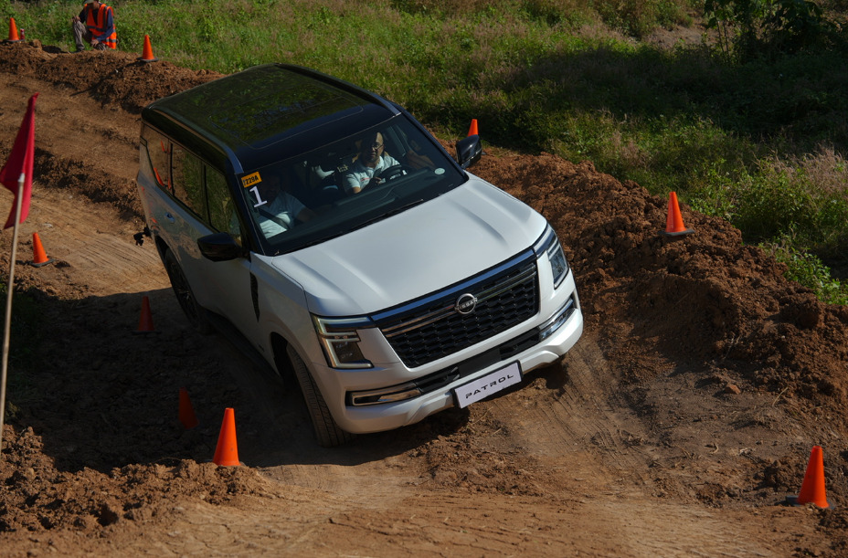 White Nissan Patrol driving on a dirt track with orange cones marking the path during an off-road activity