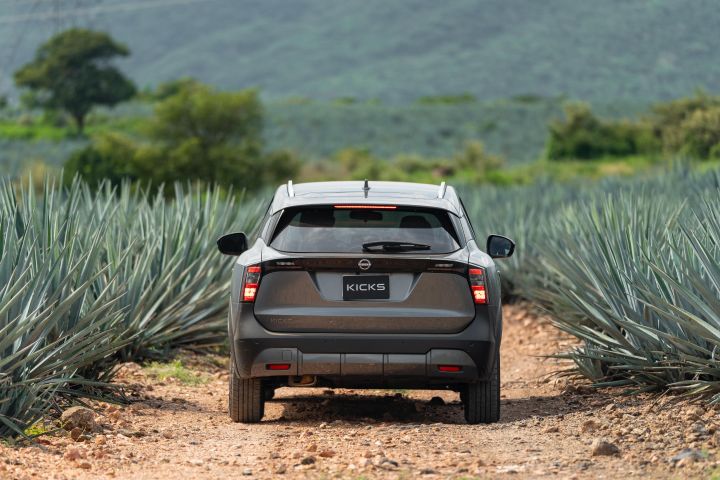 Nissan Kicks gris de la parte trasera con fondo de agaves verdes.