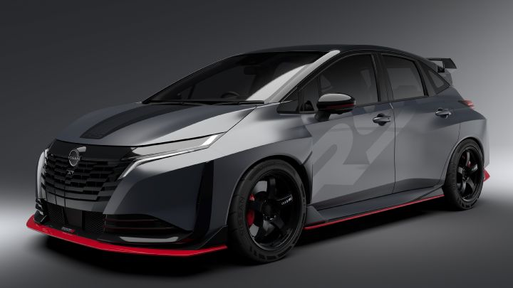 A silver and black two-tone sports car, the Aura Nismo RS Concept, photographed in a studio from a front-right angled view. The vehicle is stationary, featuring a Nissan logo on the center of the front grille and a red accent line with the 'NISMO' logo on the lower bumper. The hood has a black stripe, and the side displays a light gray  'RS.' The background is a simple gray gradient, highlighting the car's sharp and sporty design