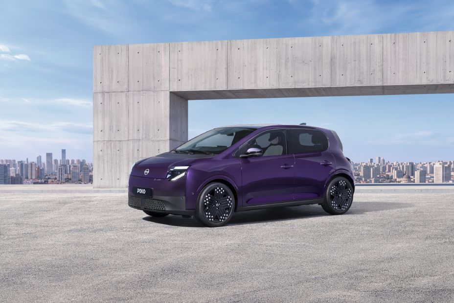 Vista frontal en tres cuartos de un Nissan PIXO eléctrico morado aparcado en un entorno urbano moderno.