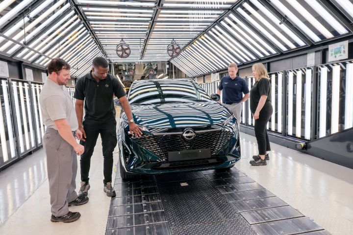 Vier Nissan Mitarbeiter begutachten einen dunkelgrünen Nissan Qashqai, der die Produktionslinie im Nissan Werk Sunderland verlässt