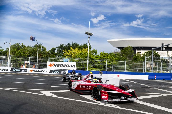 Front- / Seitenansicht von Oliver Rowland im Auto mit der Startnummer 1 während des E-Prix von Sanya, hinter ihm ist ein weiteres Auto zu sehen, als er aus der Kurve herausfährt.