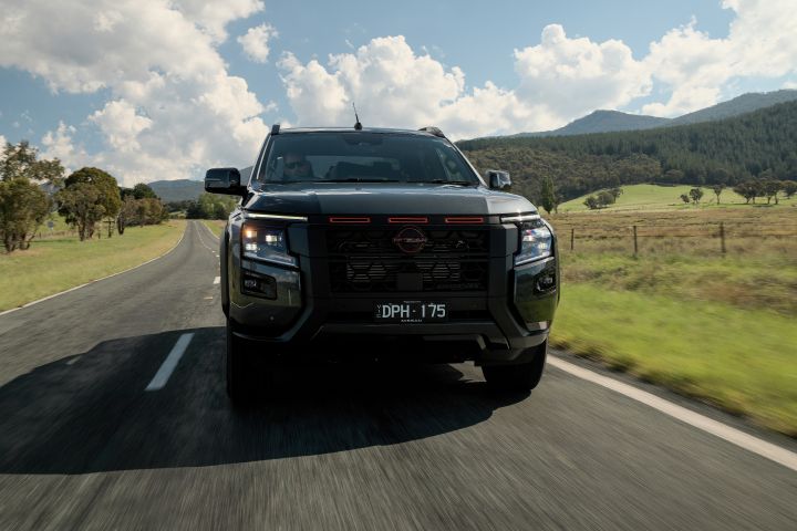2026 Nissan Navara PRO-4X finished in Boulder Grey illustrating a straight-on driving scene with broad valley views, fence posts and rolling hills.