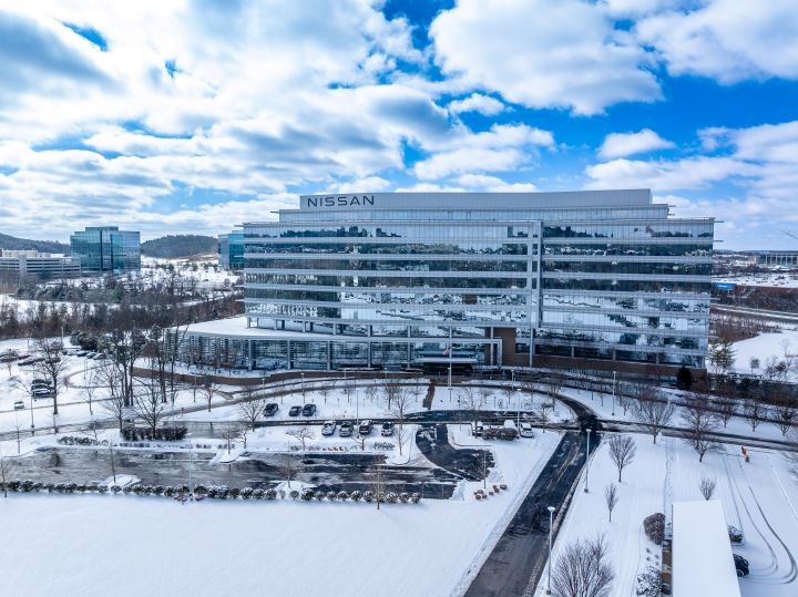 Front of NNA headquarters building and parking lot, snow covers the ground and trees, the sky is bright blue.