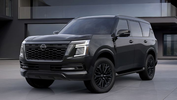 Front three-quarter view of a black Nissan Armada Dark Armor parked in front of a modern architectural building.