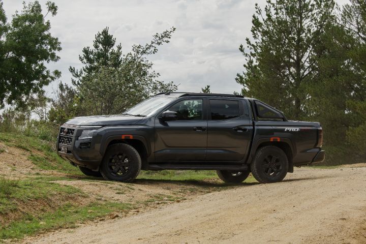 2026 Nissan Navara PRO-4X finished in Boulder Grey presented in a straight side profile on an incline with sports bar silhouette, black wheels and sculpted body sides.