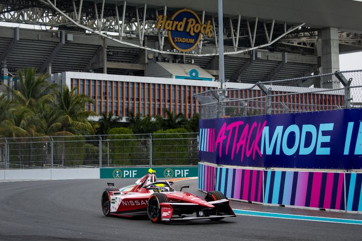 Monolugar vermelho da Nissan Formula E Team visto de ¾ em pista com Hard Rock de fundo