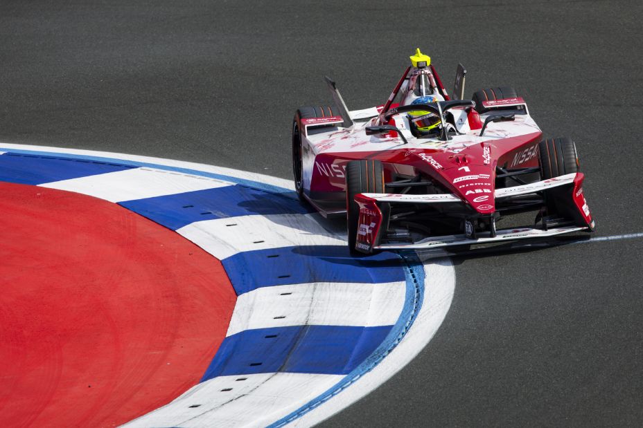 Front on shot of Oliver Rowland in the #1 Nissan e‑4ORCE 05 on-track turning right into a corner going across the blue and white curb.