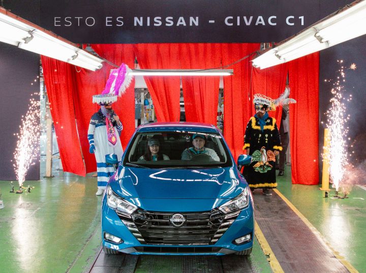 Nissan Versa Azul con dos colaboradores en el interior. Fuegos artificiales y dos personas vestidas de chilenos, traje típico de Morelos, en donde se ubica Planta Civac.