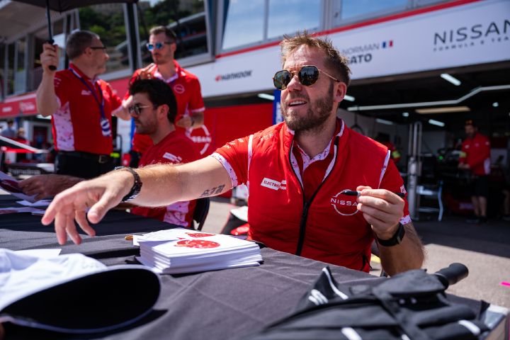 Sam Bird mit Sonnenbrille und seiner roten Teamweste bei einer Autogrammstunde.