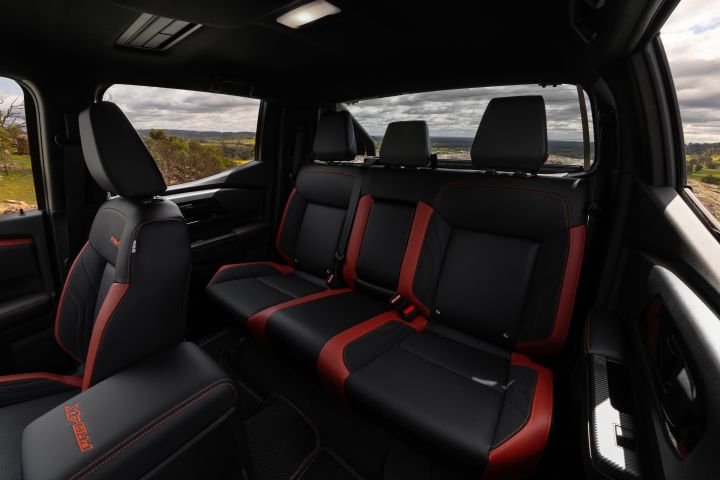 2026 Nissan Navara PRO-4X finished in Boulder Grey capturing the rear cabin with a three-seat bench, red inserts, headrests and scenery through the windows.