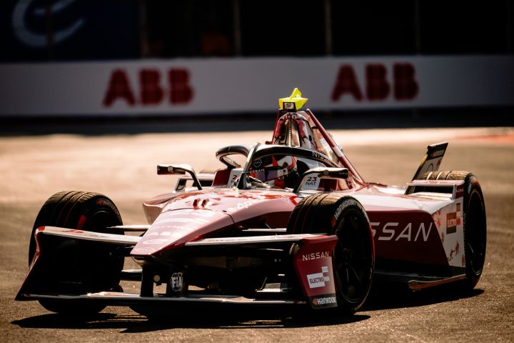 Frontalaufnahme von Norman Nato im Nissan Formel E Rennwagen mit der Startnummer 23 auf der Rennstrecke mit weißen Werbetafeln von ABB im Hintergrund.