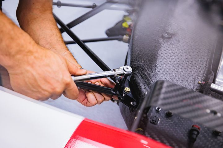 Ein Mechaniker zieht eine Schraube am Nissan Formel E Rennwagen fest