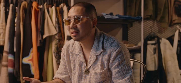 A photo of Emil wearing sunglasses and polo shirt sitting inside his shop while doing some interview.