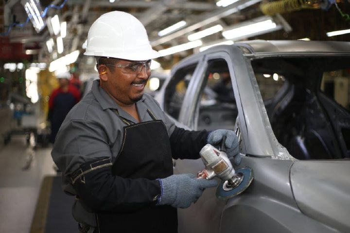 Un colaborador de Planta Civac con su uniforme y casco, puliendo una unidad en línea de producción actual.