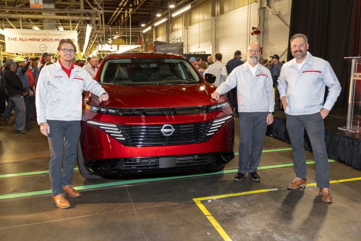 Three men in silver Nissan Jackets stand smiling in front of a red 2025 Nissan Murano.