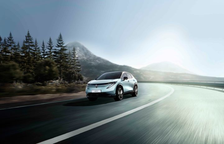 Opdateret Nissan Ariya kørende i skoven, hvor man kan se den coupe inspirerede SUV profil.