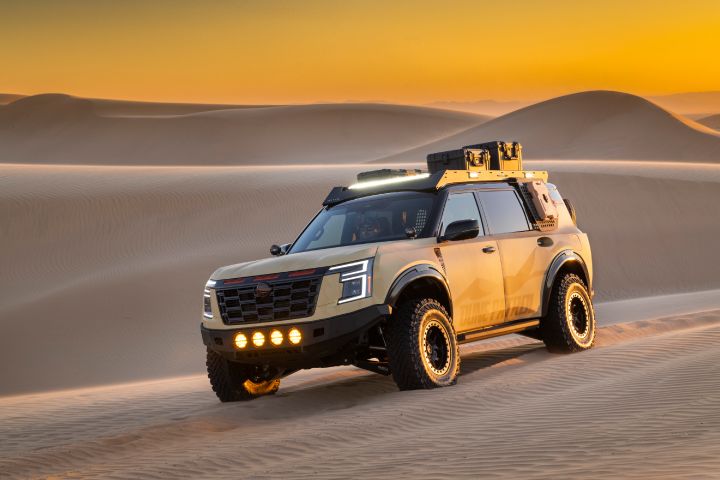 Front left 3/4 angle of the Nissan Dune Patrol SEMA build driving on sand at sunset.