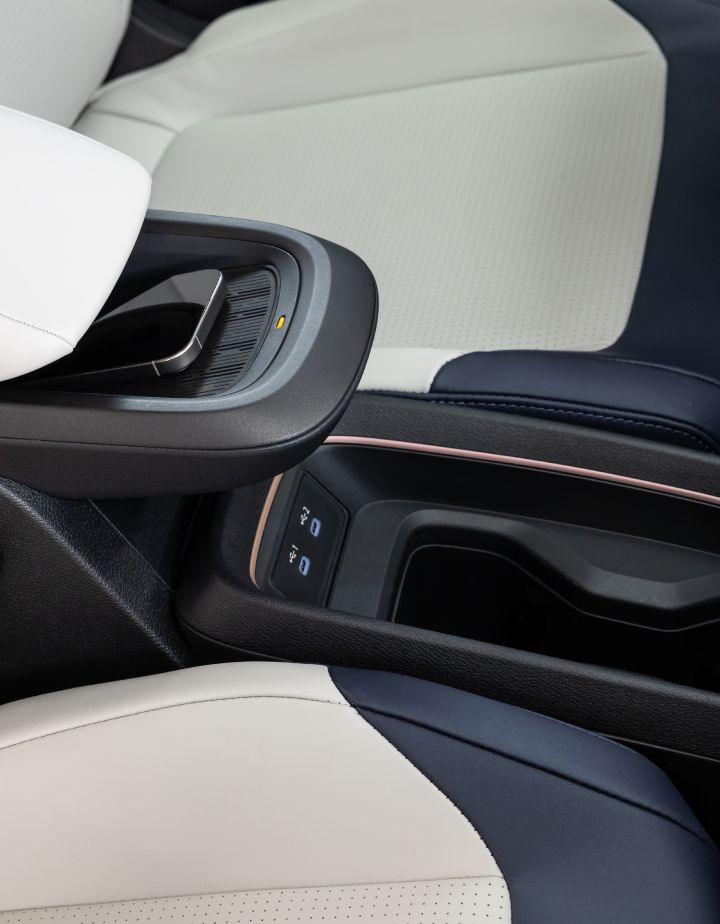 Détail de la console centrale de l'habitacle de la Nissan LEAF avec l'accoudoir et un téléphone posé sur le chargeur