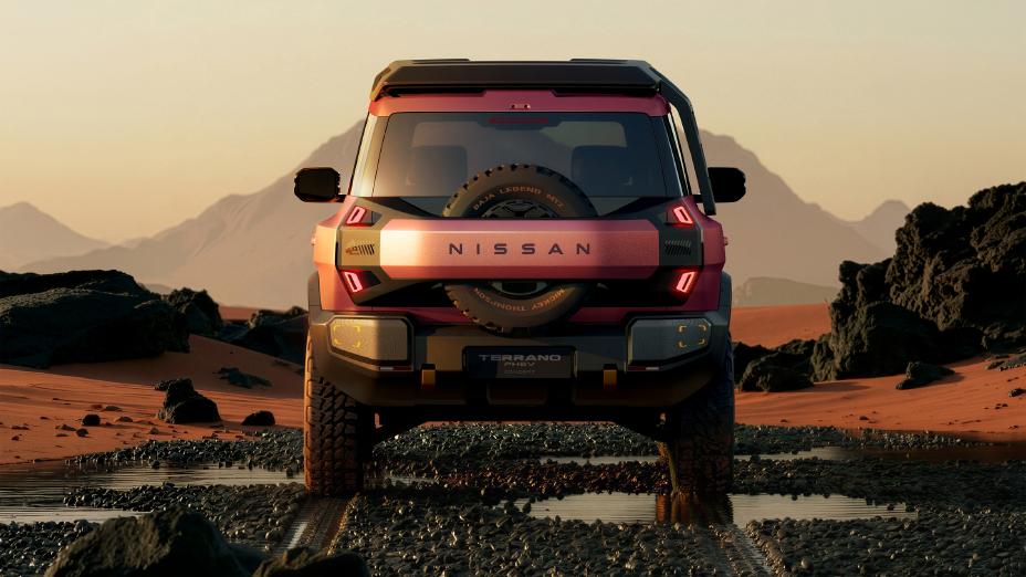 A red Terrano PHEV Concept driving toward the viewer in a desert at sunset. Rocky and sandy terrain surrounds the vehicle, with puddles in the foreground and distant mountains under a soft evening sky.