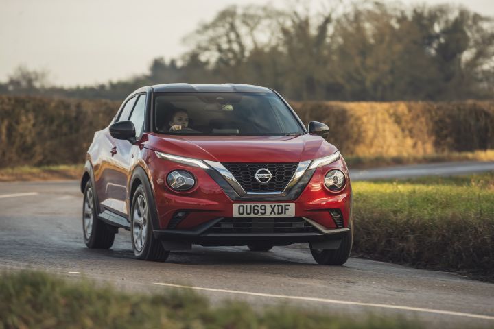 A woman in a Red Nissan Juke driving down a country road