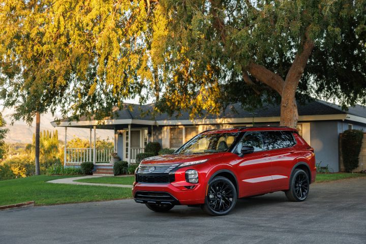 Front left 3/4 view of a 2026 Nissan Rogue Plug-in Hybrid parked under a tree in front of a home