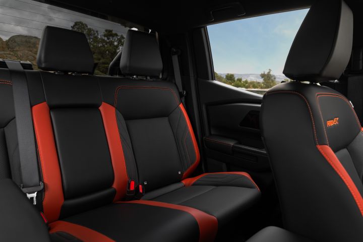 2026 Nissan Navara PRO-4X finished in Boulder Grey capturing the rear-seat cabin with three-seat bench, red side bolsters and front seatback embroidery.