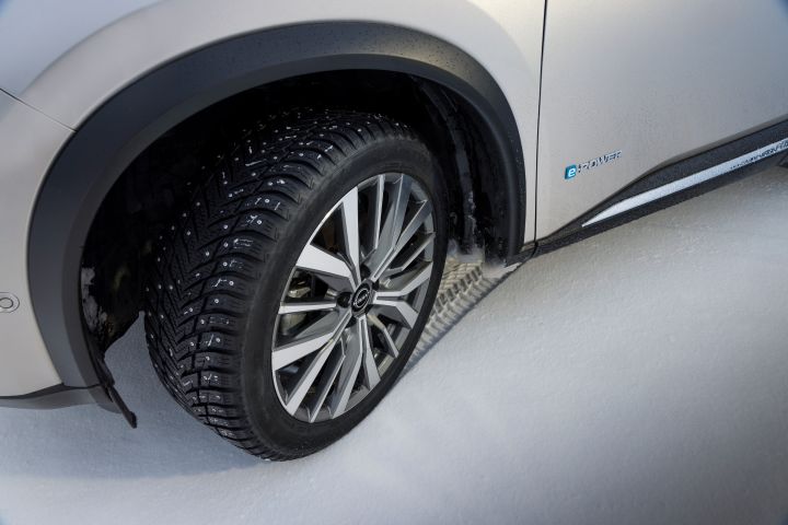 Detailansicht Leichtmetallräder und Reifen des Nissan X‑Trail auf Schnee schräg von vorne-oben