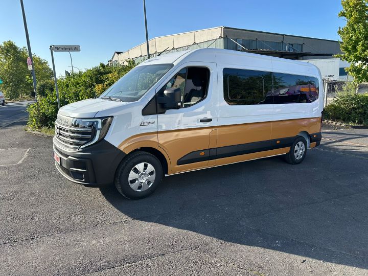 Seitenansicht eines im Sonnenschein geparkten Nissan Interstar-e mit Umbau von Eifelland, die untere Fahrzeughälfte ist orange lackiert und die obere weiß.