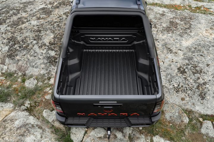 2026 Nissan Navara PRO-4X finished in Boulder Grey viewed from above over the cargo tub with embossed NAVARA bulkhead and tow hitch.