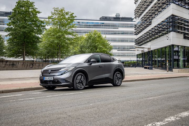 Am Rand einer städtischen Straße steht ein grauer Nissan Leaf vor mehreren modernen Hochhäusern